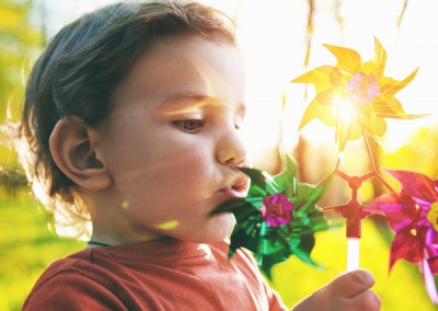 Portrait of a cute boy blowing wind wheel in sunshine